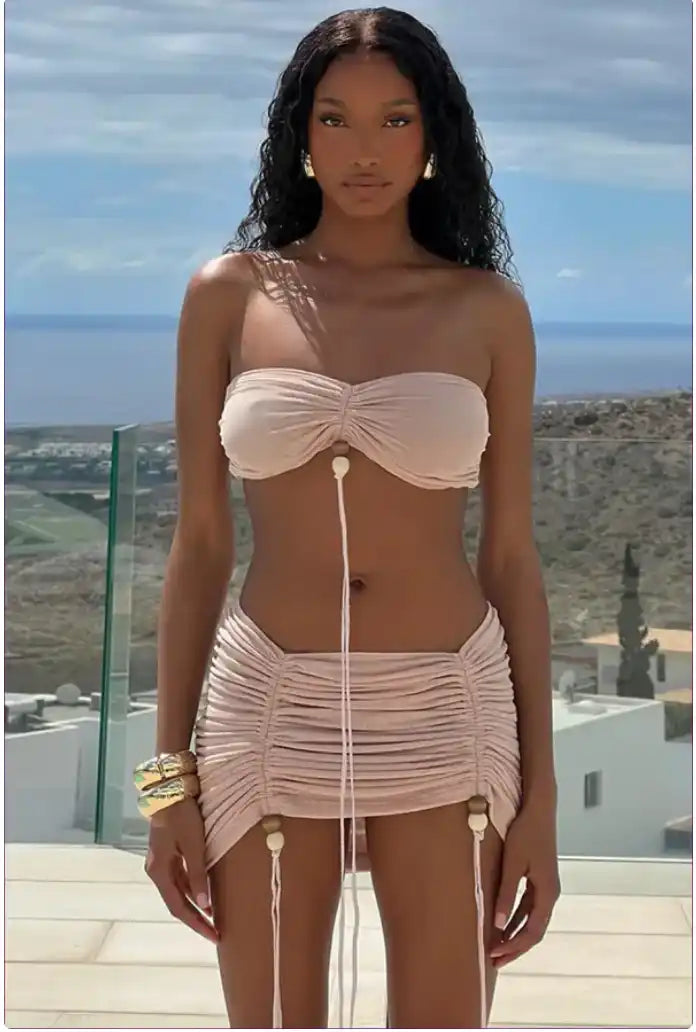 A cream-colored ruched two-piece swimsuit with drawstring details.