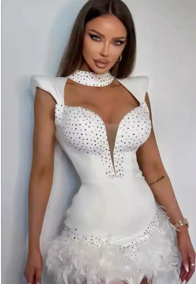 A form-fitting white dress with crystal embellishments, structured shoulders, and a ruffled tulle skirt.